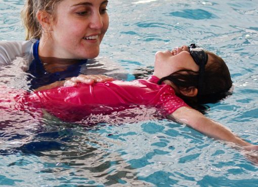 Swim instructor helps an infant feel comfortable in the water